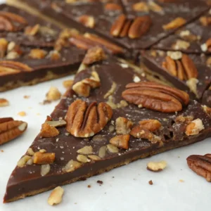 Pecan Pie Bark Irresistibly Tasty and Simple to Make 4 Close-up of pecan pie bark with rich chocolate, toasted pecans, and caramelized bits scattered across the surface, with irregular broken pieces.
