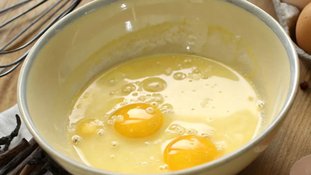 Eggs added to a bowl of creamed butter and sugar, ready to be mixed for cookie dough.
