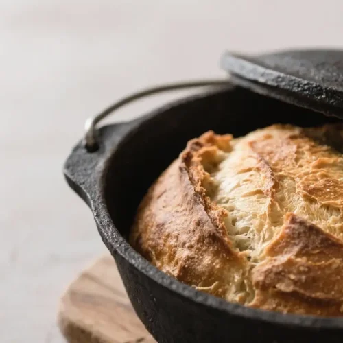 Crusty homemade Dutch oven bread with a golden crackled crust baked in a cast iron pot.