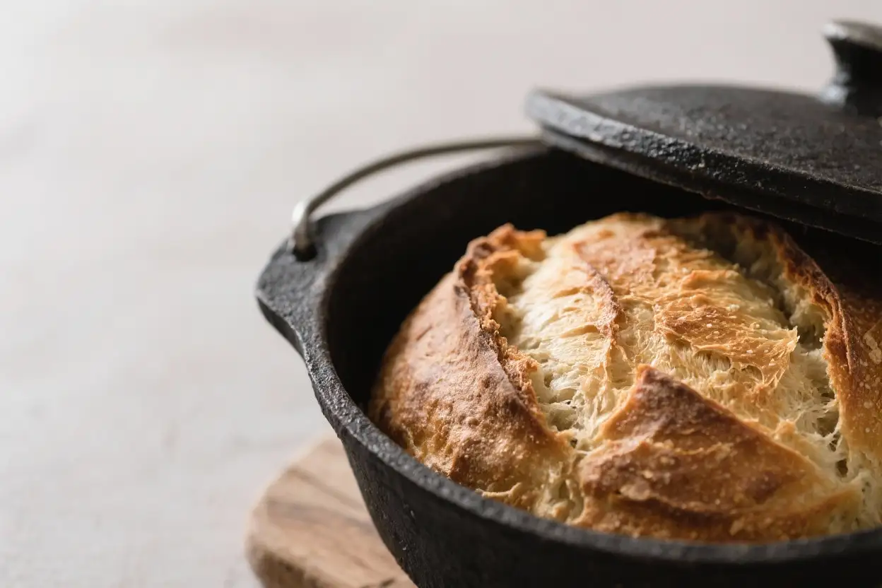 Crusty homemade Dutch oven bread with a golden crackled crust baked in a cast iron pot.
