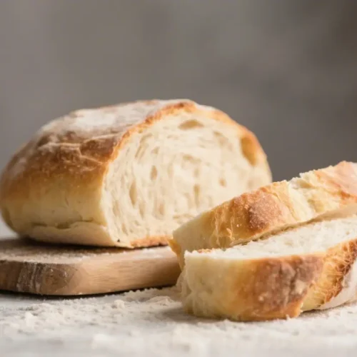 No knead bread loaf sliced on a wooden board with a golden crust and soft airy interior