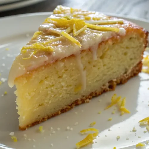 The Best Homemade Lemon Cake (Soft, Zesty & Easy) - Bright Flavor, Foolproof Method 2 Slice of moist lemon cake topped with glossy lemon glaze and fresh lemon zest on a white plate