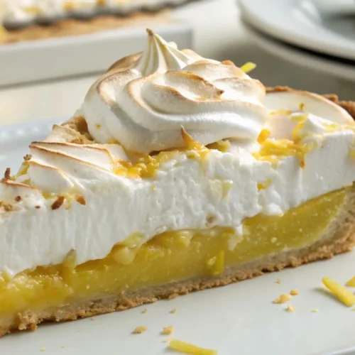 Slice of lemon meringue pie with tangy lemon filling and fluffy toasted meringue on a crisp pie crust.