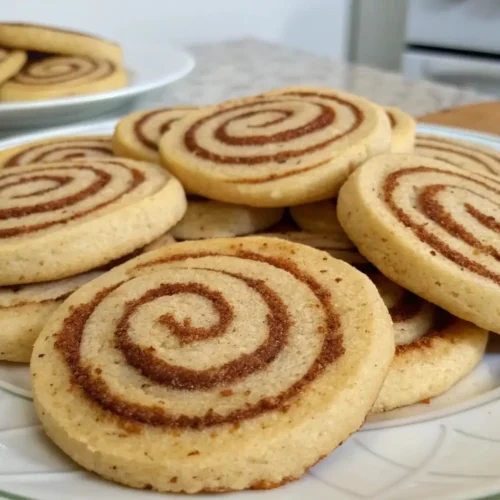 Easy Cinnamon Sugar Swirl Cookies Bakery Style Treat - Soft, Buttery, and Irresistible 3 Close-up of cinnamon swirl cookies arranged on a white plate, showing spiral layers of cinnamon sugar baked into soft, golden cookies.