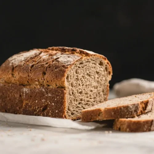 Homemade deli rye bread loaf with rustic crust and sliced pieces on parchment