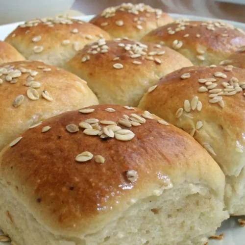 Soft Oatmeal Dinner Rolls Easy Homemade Recipe - Fluffy, Cozy, and Foolproof 2 Close up of soft oatmeal dinner rolls topped with oats, golden brown and fluffy inside, served on a white plate.
