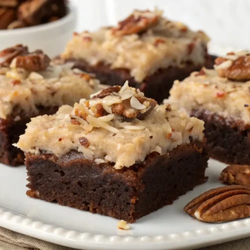 German chocolate brownies topped with coconut pecan frosting, rich chocolate base with creamy textured topping served on a white plate