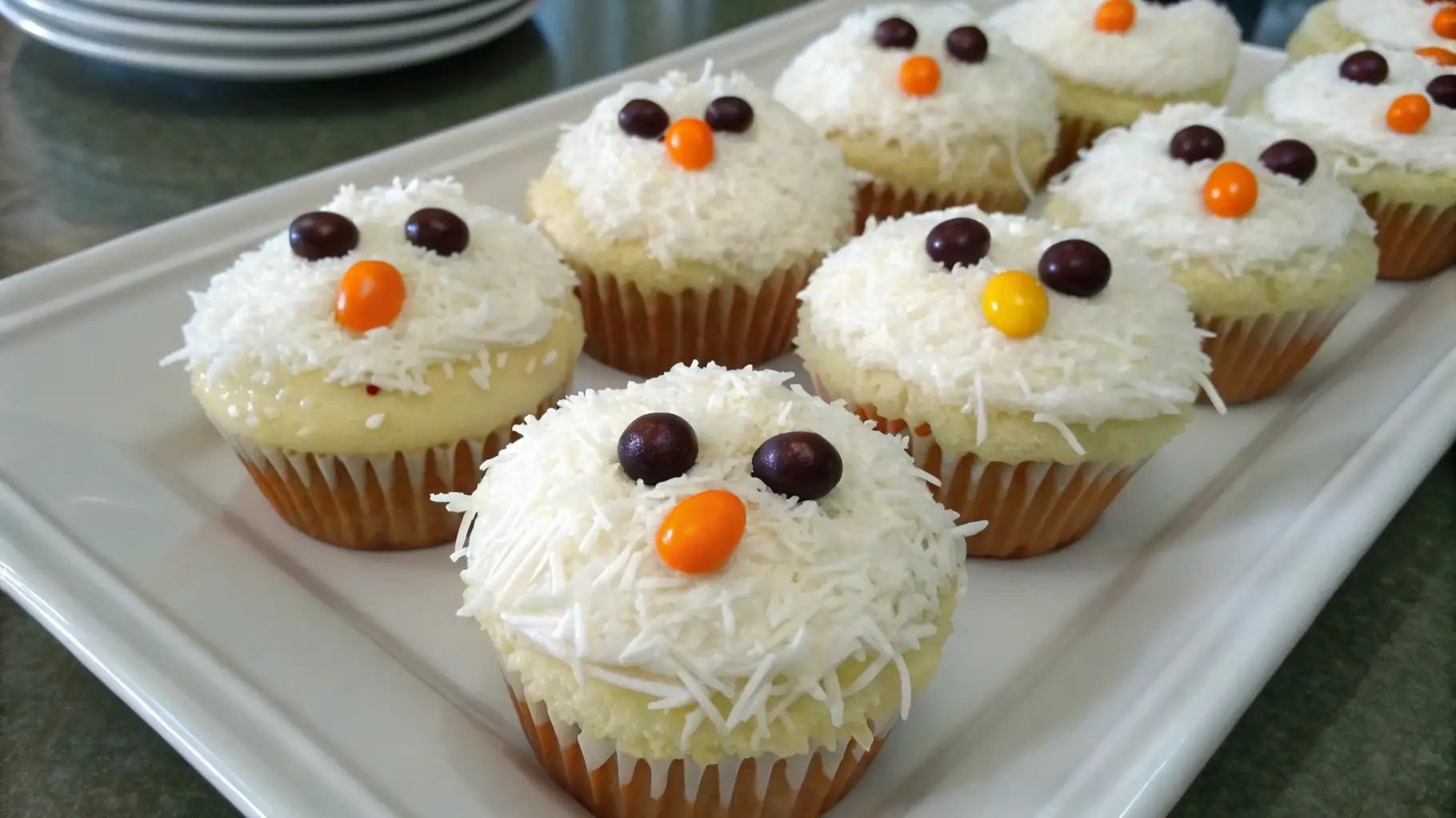 Cute Chicken Cupcakes Recipe for Parties and Kids Snacks - Fun, Easy, and Adorable 1 Cute chicken cupcakes decorated with white coconut frosting, candy eyes, and orange candy beaks arranged on a white plate for a fun party dessert