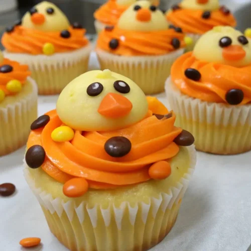 Easy Duck Cupcakes Decorating Ideas for Beginners - Cute, Fun, and Foolproof 2 Cute duck-themed vanilla cupcakes with orange buttercream frosting and candy decorations on a baking tray