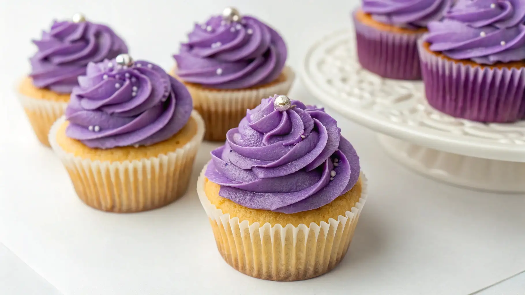 Cute Purple Cupcakes for Weddings, Birthdays and Events - Soft, Elegant, and Easy 1 Purple frosted cupcakes with vanilla base and smooth buttercream swirls topped with silver sprinkles on a white background