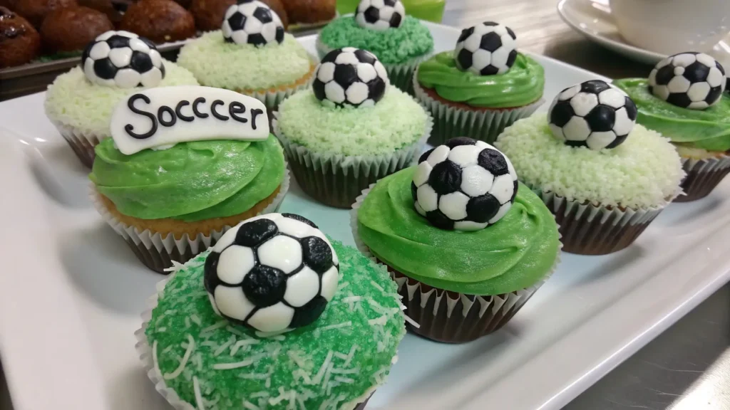 Soccer cupcakes decorated with green frosting and mini soccer ball toppers on a serving tray